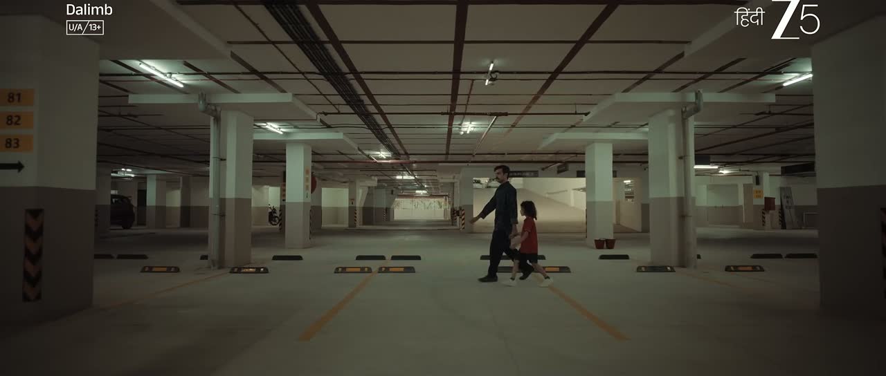 A man and a child crossing an empty underground car park, from Dalimb